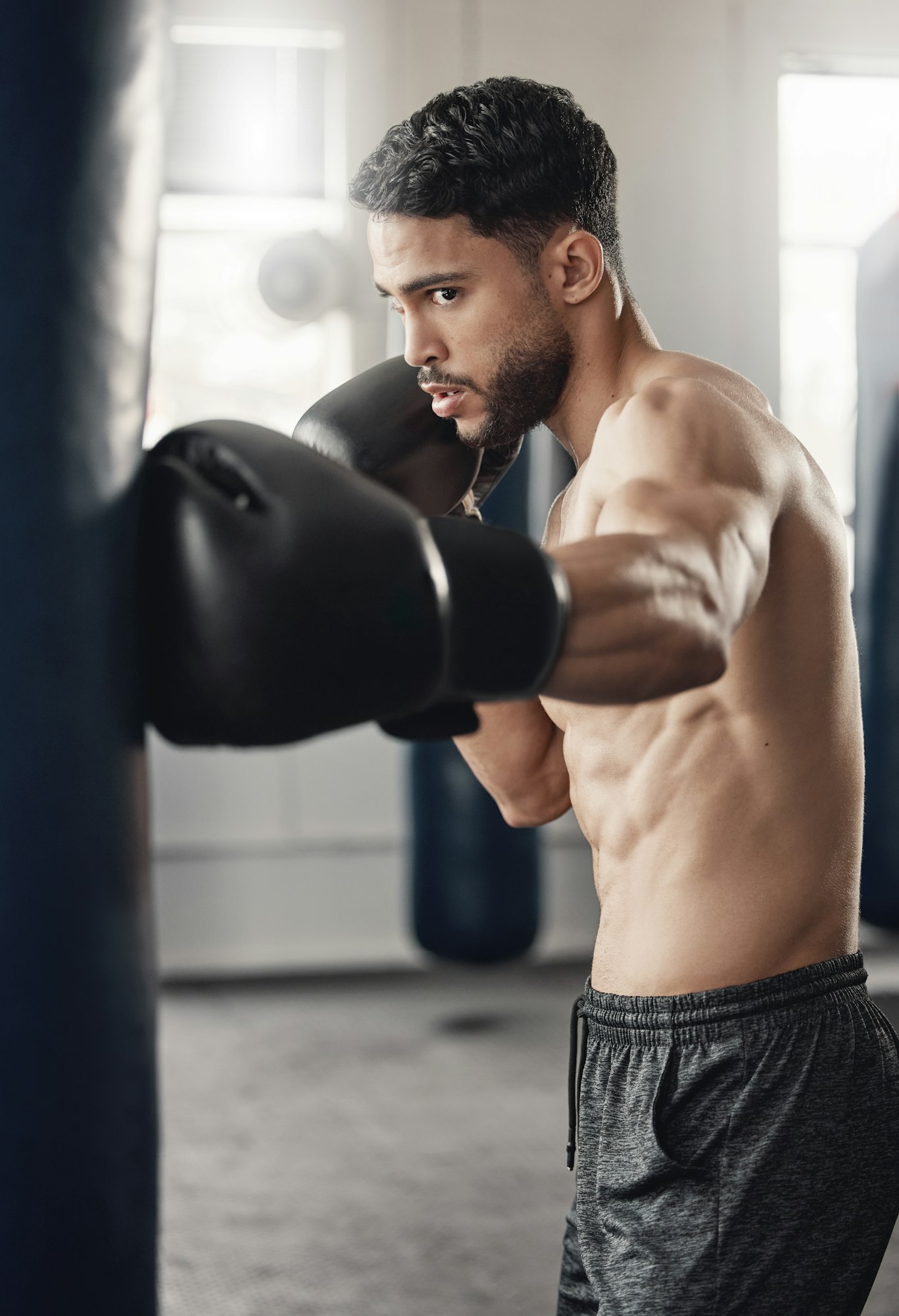 Punching bag, boxing and boxer man in workout training or exercise in a gym. Strong, powerful and s